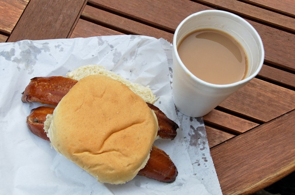 Two Caster kipper fillets in a white bread bun with a cup of tea in a polystyrene cup